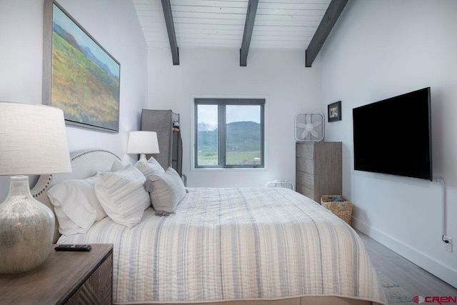 bedroom with hardwood / wood-style floors and beamed ceiling