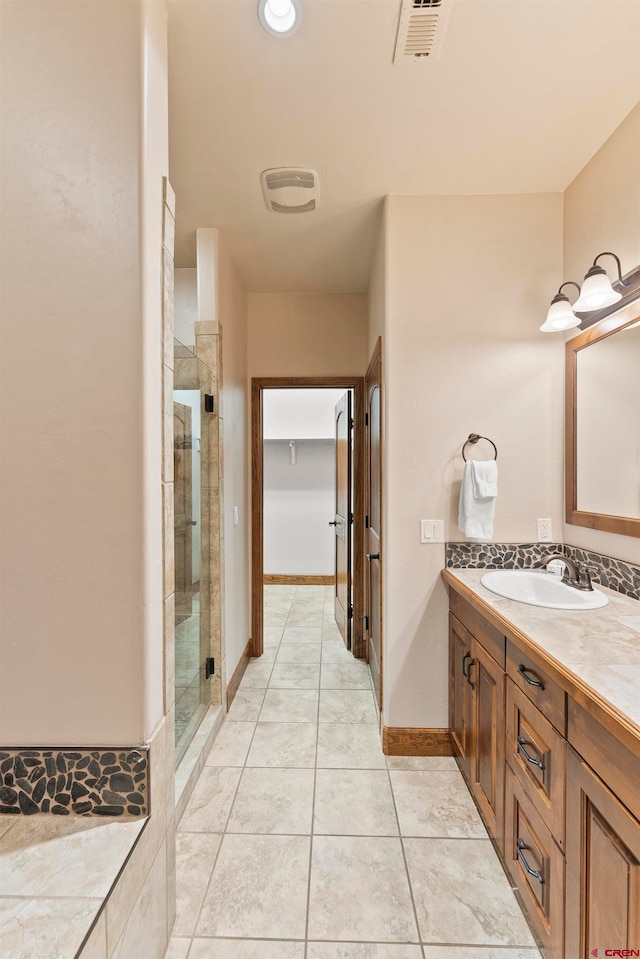 bathroom with vanity with extensive cabinet space, walk in shower, and tile flooring