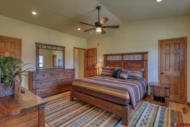 bedroom with vaulted ceiling, ceiling fan, and light wood-type flooring