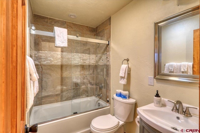 full bathroom featuring sink, combined bath / shower with glass door, and toilet