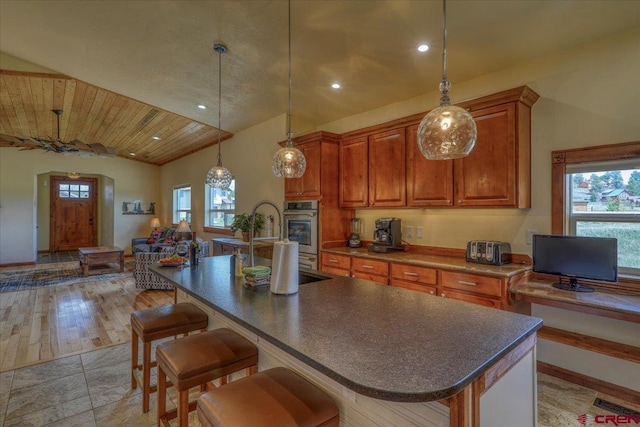 kitchen featuring pendant lighting, a breakfast bar area, oven, and a center island with sink