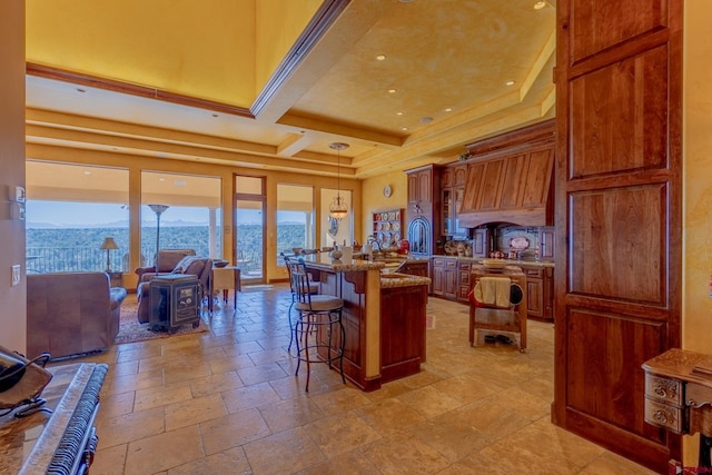 kitchen with a breakfast bar, a water view, decorative light fixtures, light stone countertops, and a kitchen island with sink