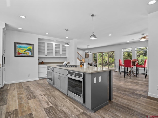 kitchen featuring stainless steel appliances, pendant lighting, dark hardwood / wood-style flooring, a center island, and gray cabinetry