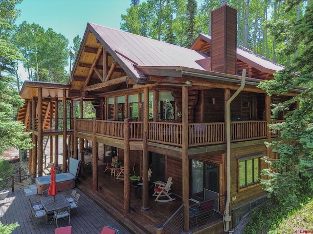 47 High Noon Ln, Telluride, CO 81435 - rear view of property featuring a wooden deck, a chimney, log siding, a covered hot tub, and a metal roof