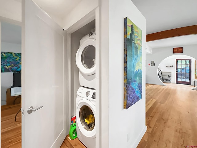 clothes washing area with wood-type flooring and stacked washer and clothes dryer