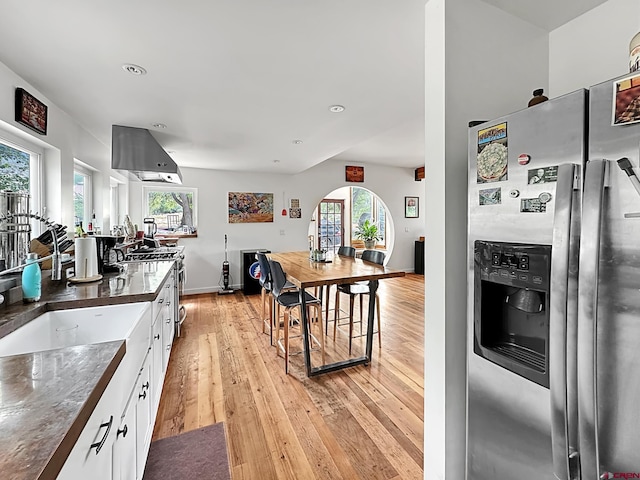 kitchen with plenty of natural light, white cabinets, stainless steel refrigerator with ice dispenser, and light hardwood / wood-style flooring