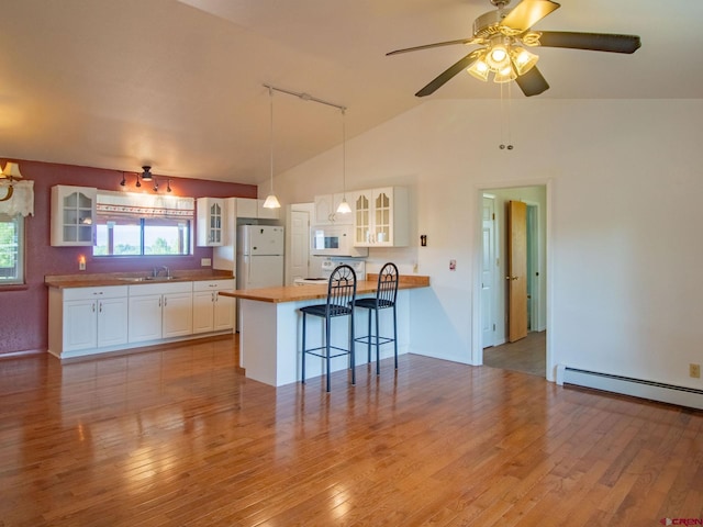 kitchen with white appliances, white cabinets, light hardwood / wood-style floors, and vaulted ceiling