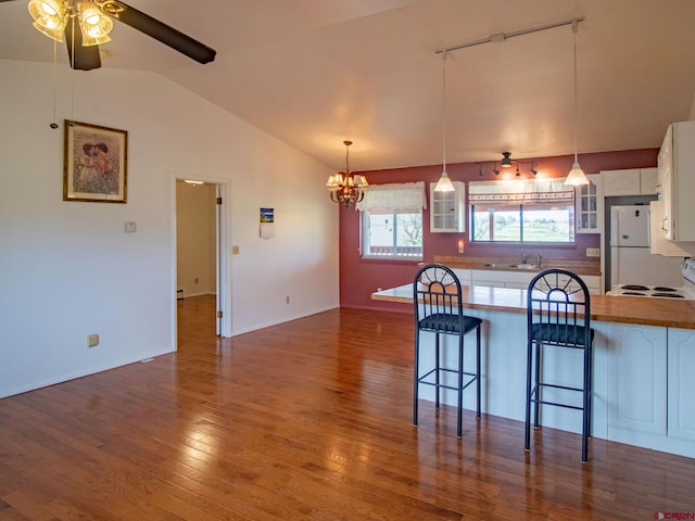 kitchen with ceiling fan with notable chandelier, white cabinets, a breakfast bar area, and wood-type flooring