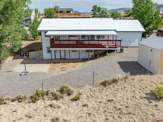 back of house with a wooden deck and a shed