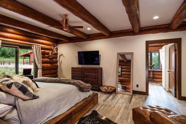 bedroom with ceiling fan, beam ceiling, light wood-type flooring, and log walls