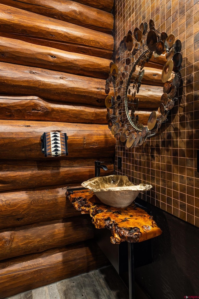 bathroom with log walls and hardwood / wood-style floors