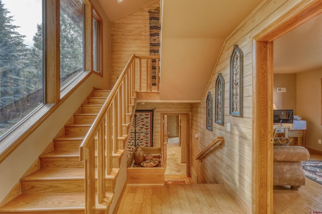 staircase with lofted ceiling, wood walls, and wood-type flooring