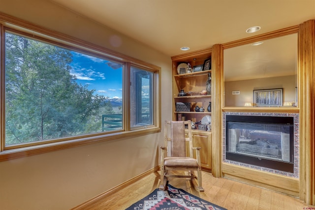 living area with hardwood / wood-style floors, a healthy amount of sunlight, and a multi sided fireplace