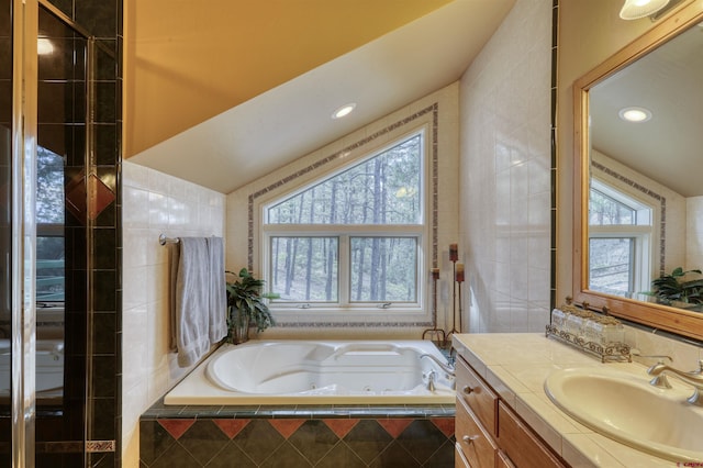 bathroom featuring vanity, a relaxing tiled tub, and tile walls