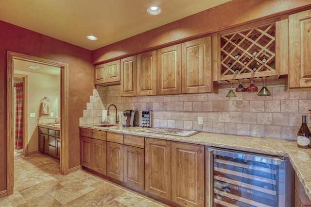 kitchen with backsplash, light stone countertops, sink, and beverage cooler