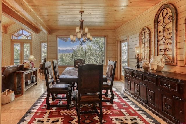 dining area with a notable chandelier, wood walls, wooden ceiling, and light hardwood / wood-style flooring