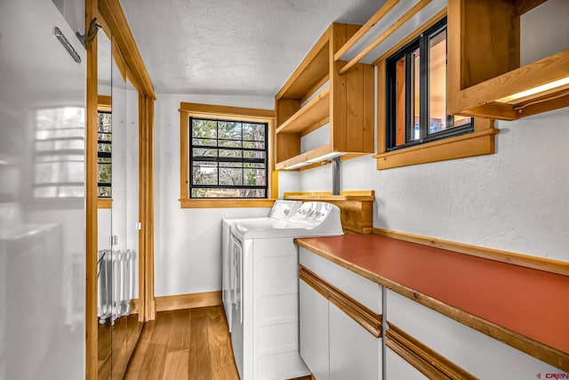 laundry room with a textured ceiling, wood finished floors, washer and dryer, laundry area, and baseboards