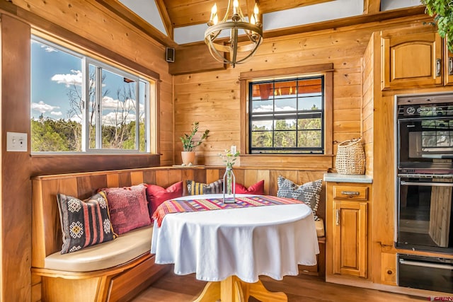 dining area with wood walls, wood finished floors, and a notable chandelier