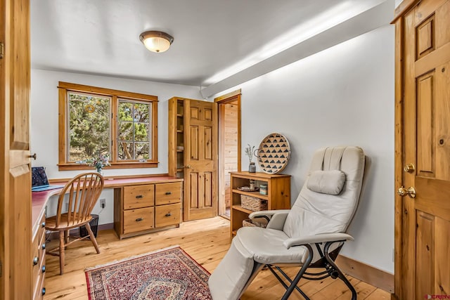 office area with light wood-style floors and built in study area