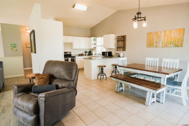 tiled dining space featuring high vaulted ceiling, a chandelier, and sink