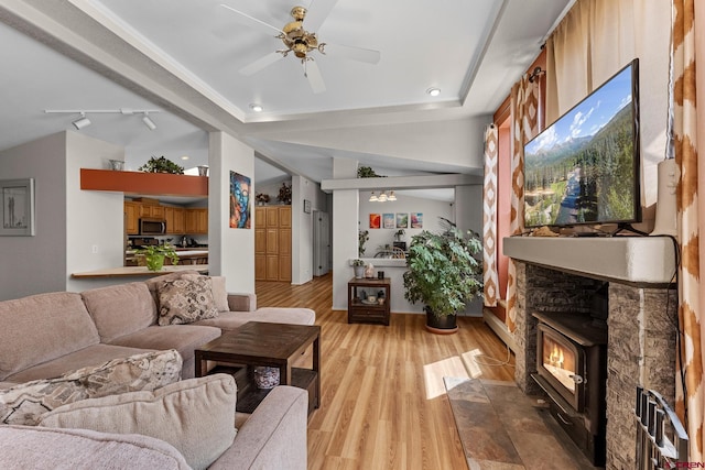 living room with ceiling fan, a fireplace, rail lighting, and light wood-type flooring