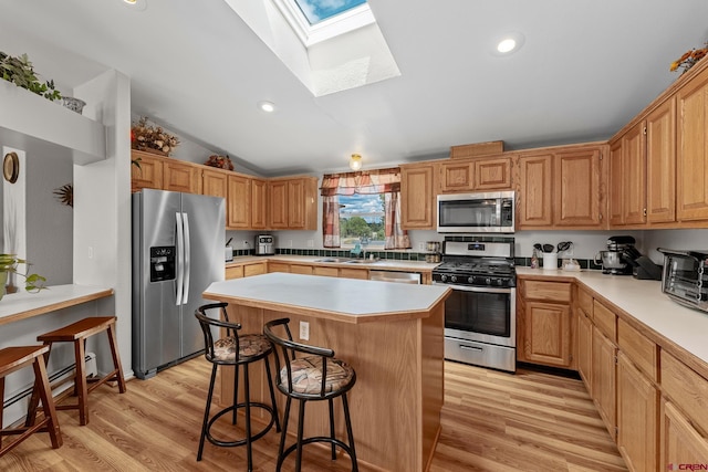 kitchen featuring a center island, sink, vaulted ceiling with skylight, light hardwood / wood-style floors, and stainless steel appliances