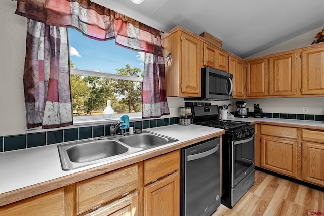 kitchen featuring light wood-type flooring, stainless steel appliances, lofted ceiling, and sink