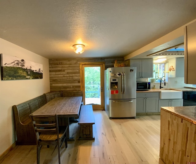 interior space featuring stainless steel fridge, dishwasher, a textured ceiling, light wood-style floors, and a sink