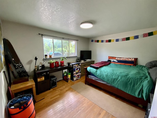 bedroom with a textured ceiling and light wood-style floors