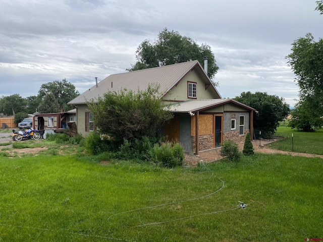 view of front of house with a front yard, stone siding, and stucco siding