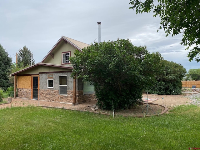 exterior space featuring stone siding, fence, stucco siding, and a yard