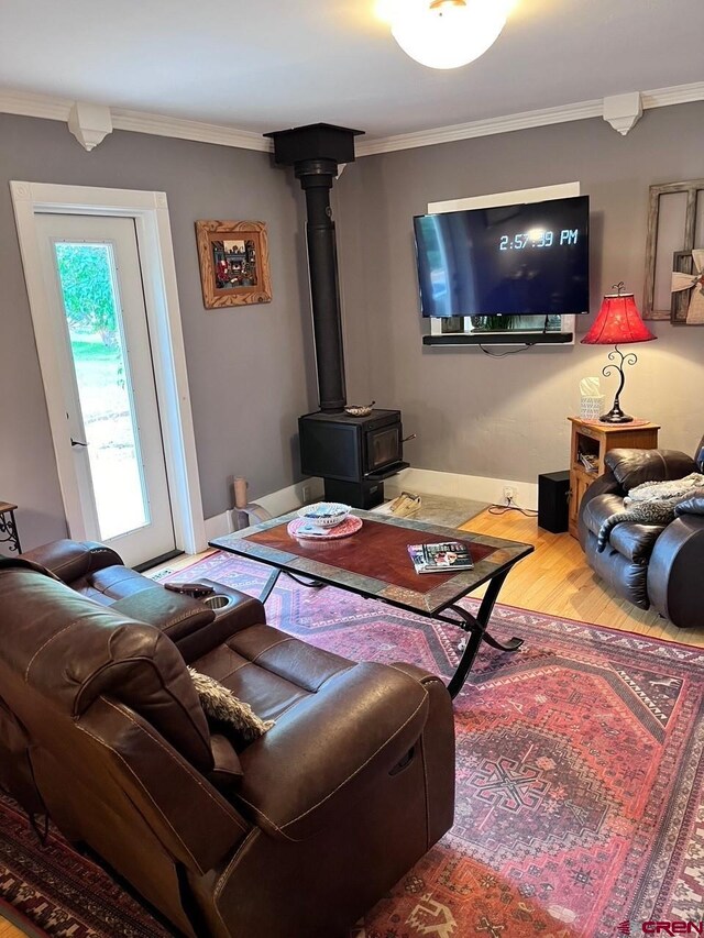 living room featuring wood-type flooring, ornamental molding, and a wood stove