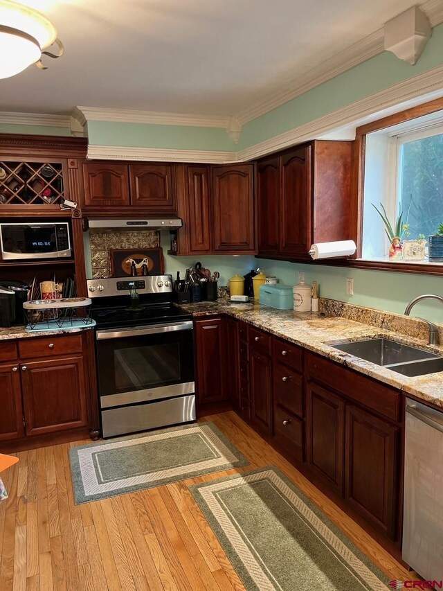 kitchen featuring crown molding, light hardwood / wood-style flooring, appliances with stainless steel finishes, light stone counters, and sink