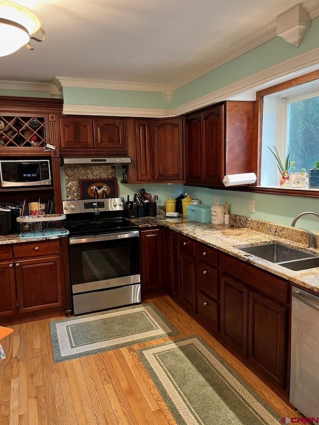 kitchen featuring light wood-style flooring, extractor fan, crown molding, stainless steel appliances, and a sink