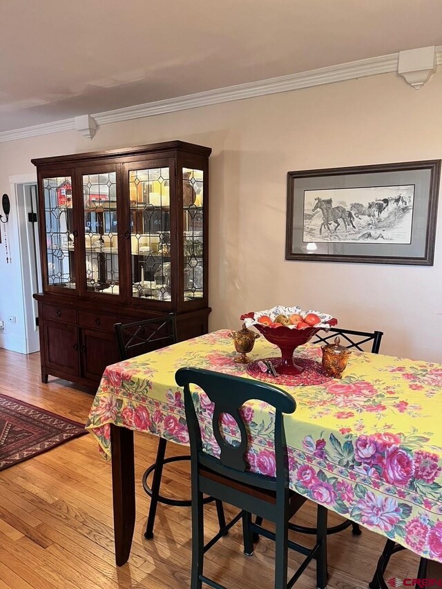 dining area with hardwood / wood-style floors and crown molding