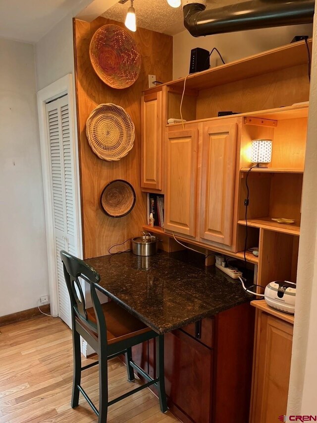 kitchen with dark stone counters, light wood-type flooring, and a textured ceiling