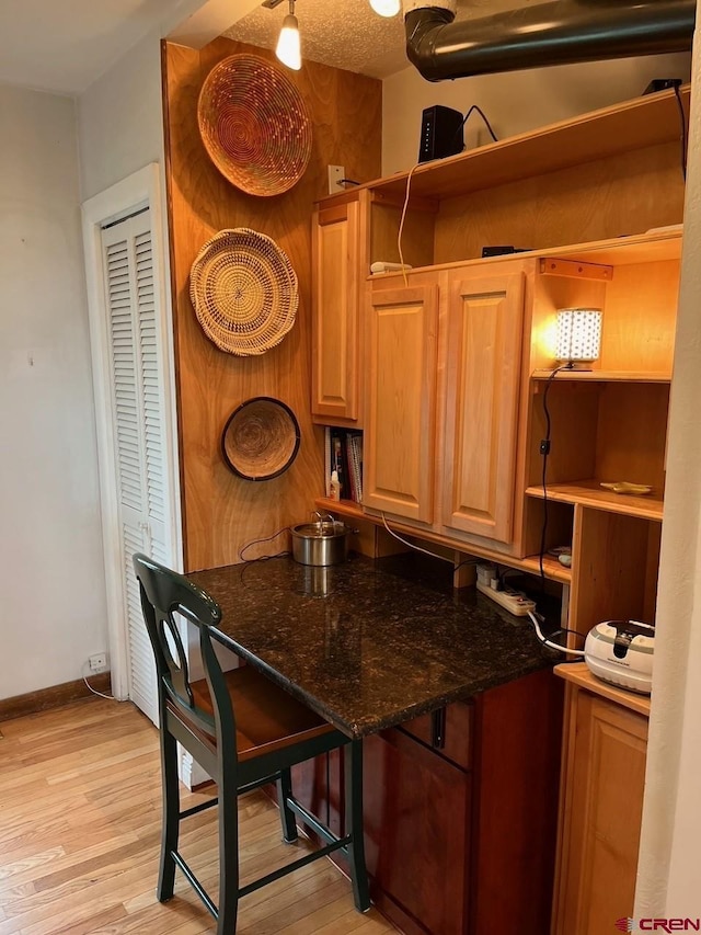 kitchen featuring dark stone countertops, baseboards, light wood finished floors, and open shelves