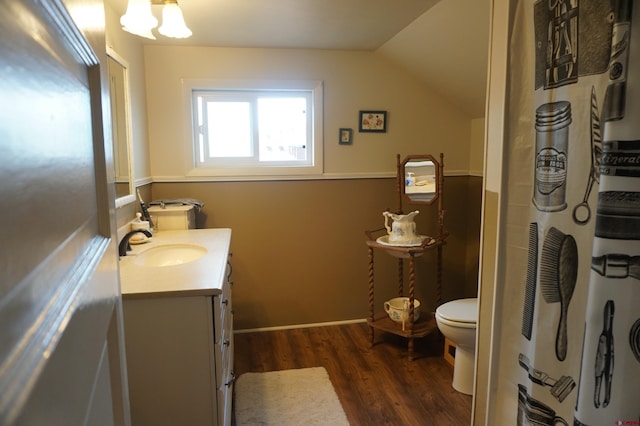 bathroom featuring toilet, wood-type flooring, vanity, and vaulted ceiling