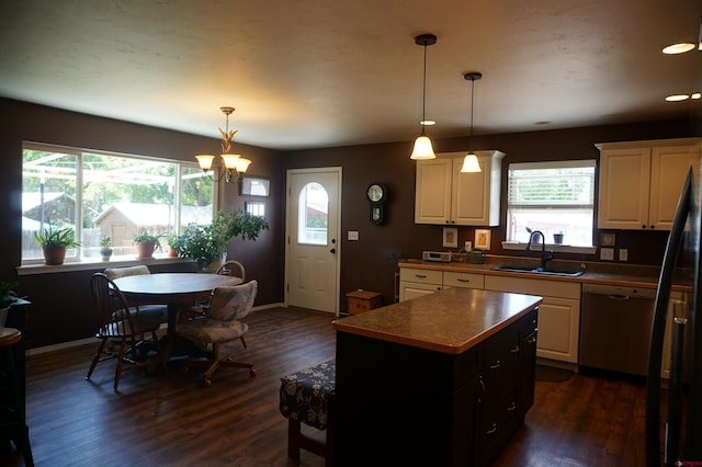 kitchen featuring decorative light fixtures, dark hardwood / wood-style floors, a kitchen island, dishwashing machine, and sink