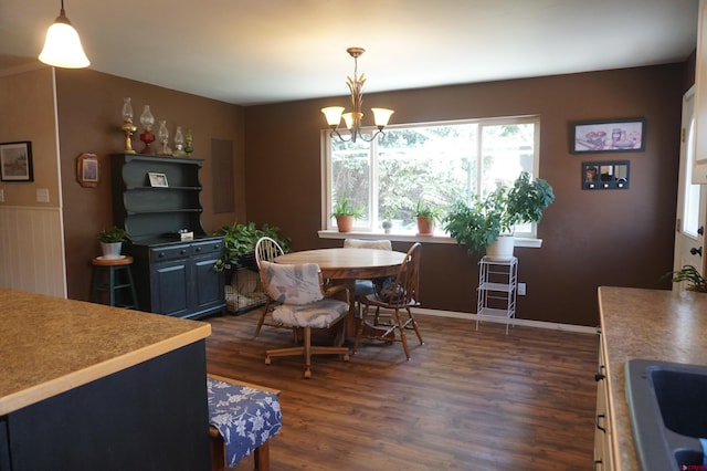 dining area featuring dark wood-type flooring, sink, and an inviting chandelier