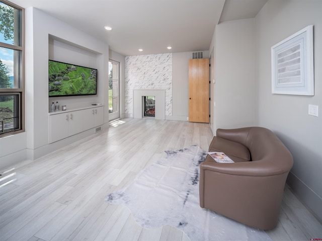 living room with a fireplace and light wood-type flooring