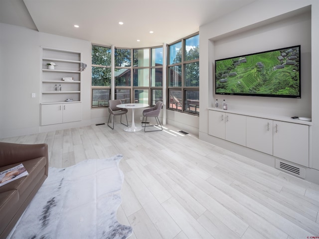 living room with light hardwood / wood-style flooring and built in features