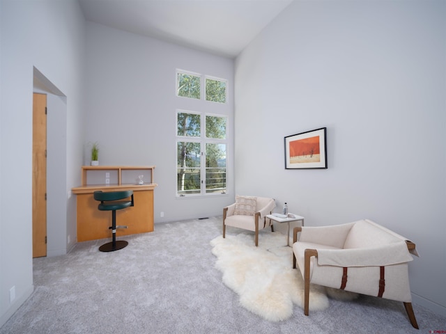 sitting room featuring a high ceiling and light carpet