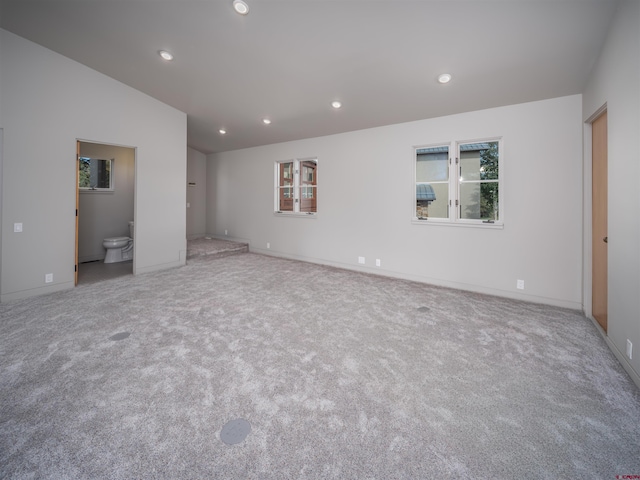 interior space with ensuite bathroom and light carpet