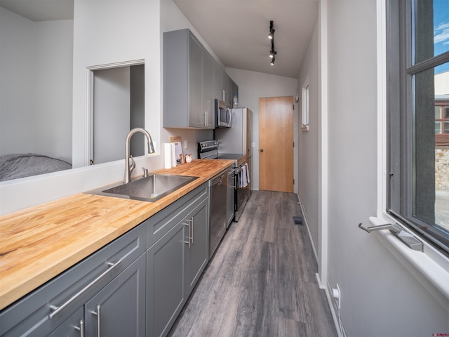 kitchen with sink, dark wood-type flooring, butcher block counters, gray cabinetry, and stainless steel appliances