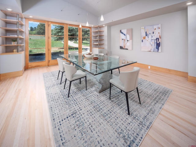 dining space featuring lofted ceiling, built in shelves, and light wood-type flooring