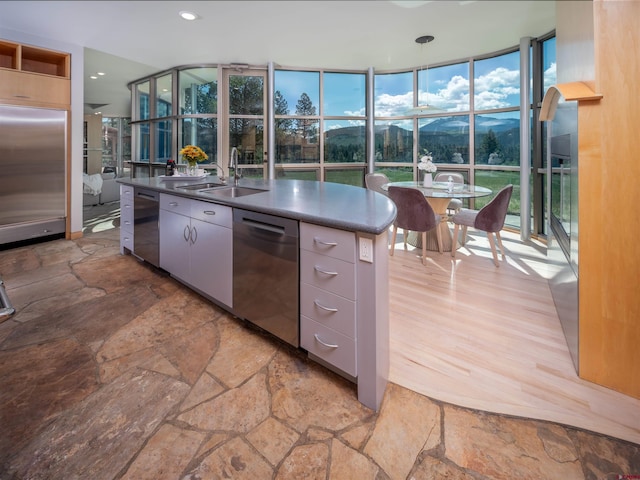 kitchen featuring decorative light fixtures, sink, a wall of windows, stainless steel appliances, and a mountain view