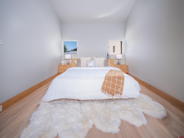 bedroom featuring lofted ceiling and light hardwood / wood-style flooring