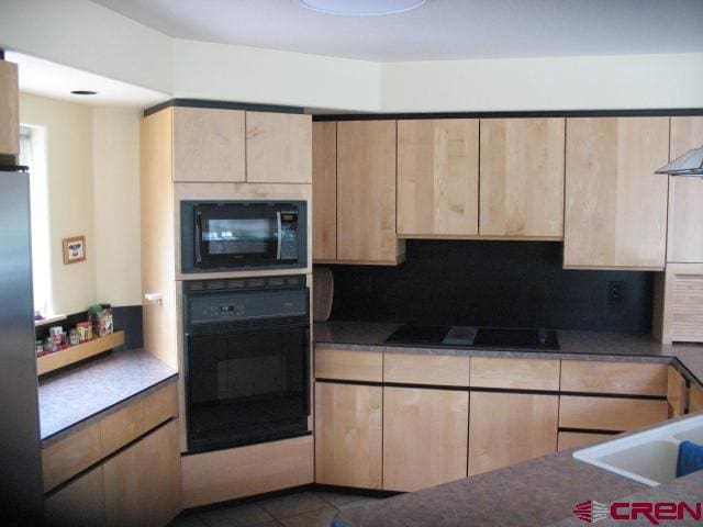 kitchen featuring dark tile floors, black appliances, backsplash, and light brown cabinetry