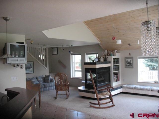 tiled living room with a multi sided fireplace and vaulted ceiling